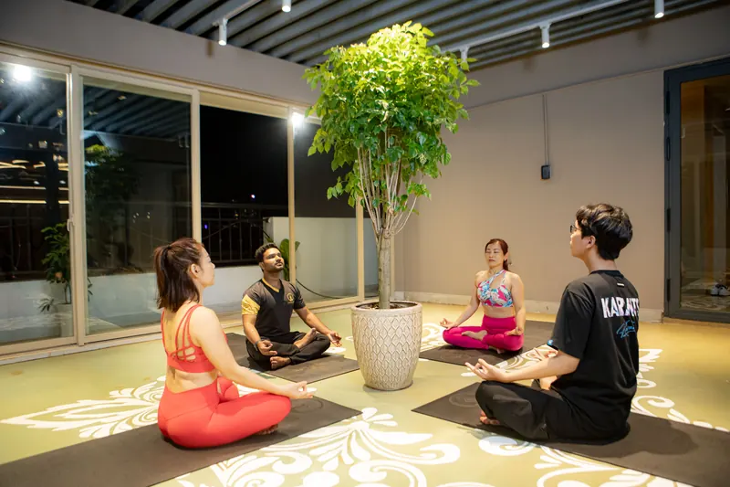 A small group seated in meditation on an open terrace