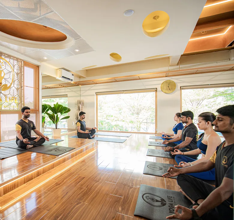 A daylit Yoga Life Premium practice room with tall windows
