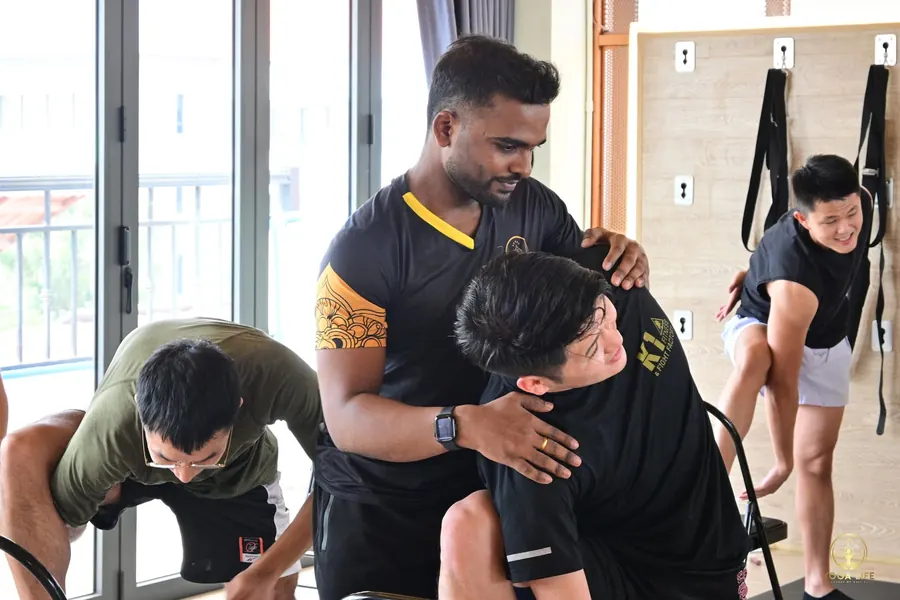A teacher giving a hands-on adjustment to a student during a class