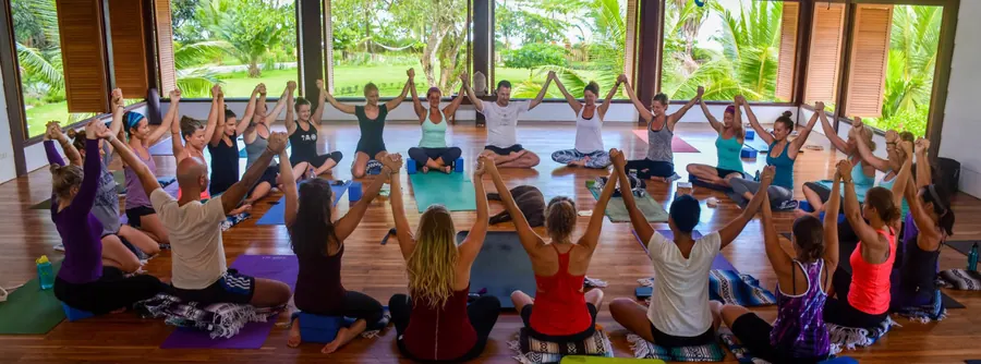 A teacher-training circle seated together with hands joined and raised