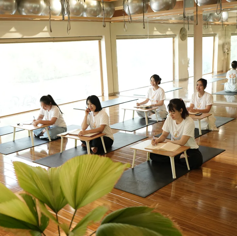Teacher-training students studying at low desks in the daylit studio